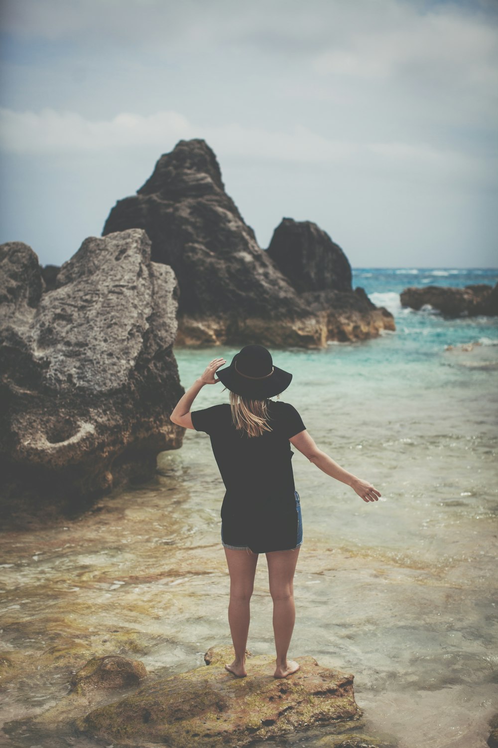 woman standing on rock seeing body of water