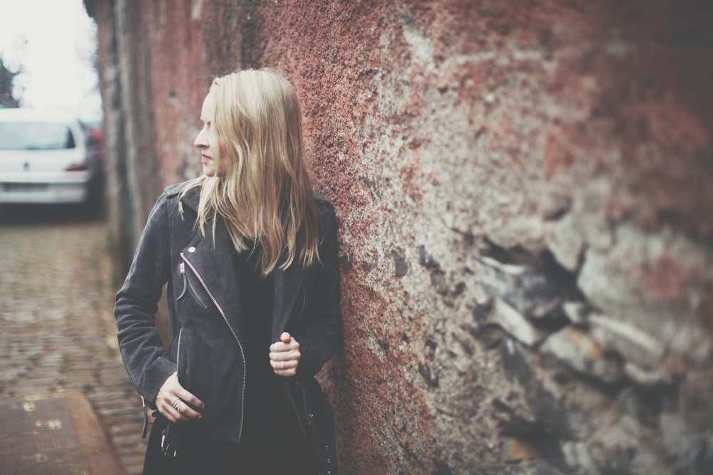 woman standing beside brown wall during daytime