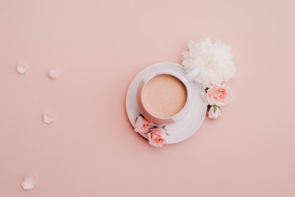 taza glaseada blanca con platillo sobre superficie rosa