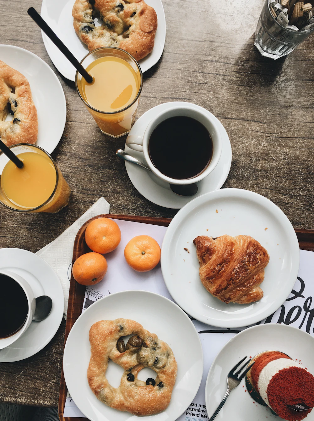 Coffee, juice, croissants and pastries on a wooden cafe table