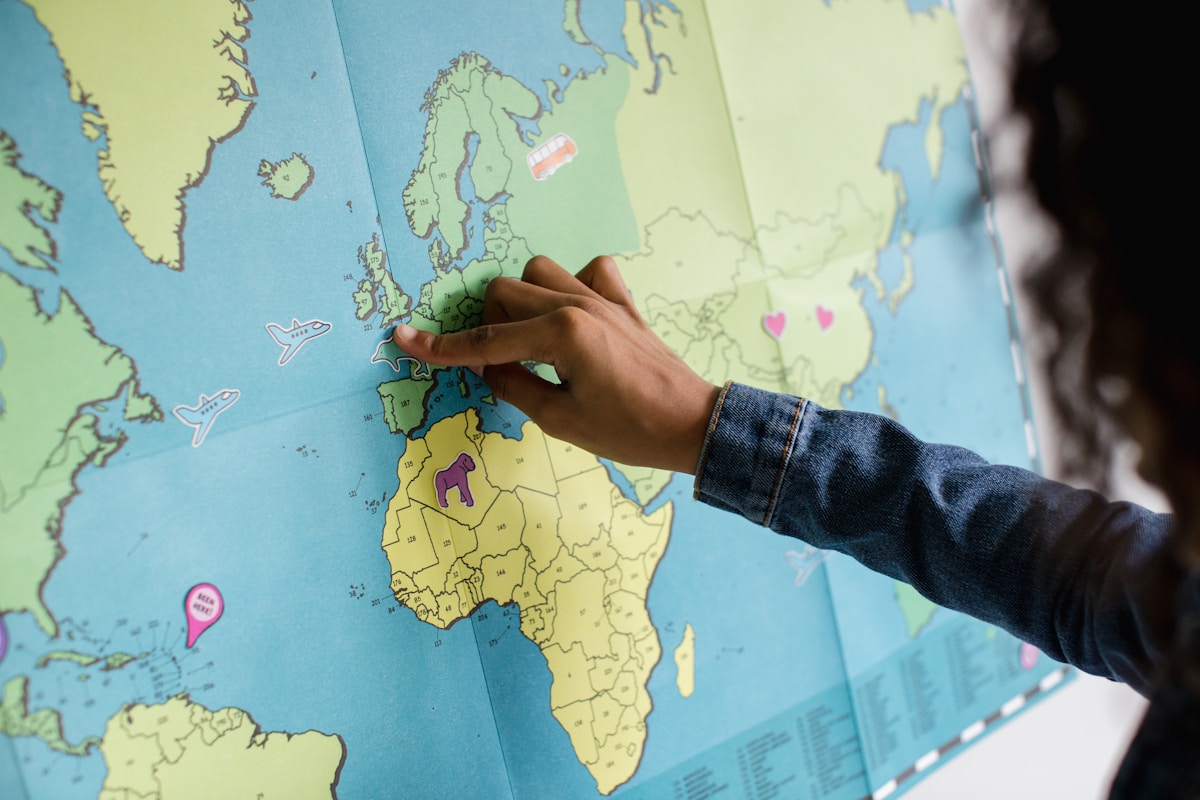 Black female putting travel and airplane stickers on a map
