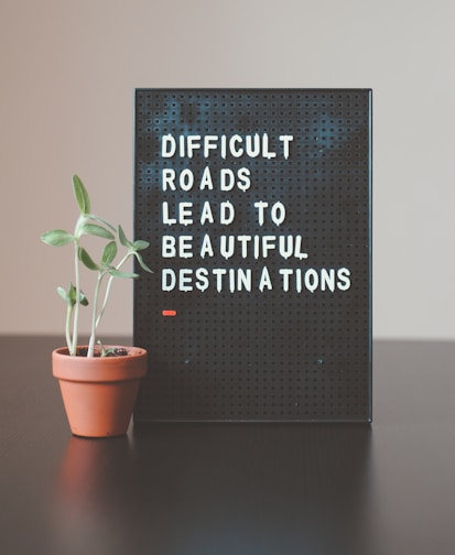 Inspirational quote on a signboard: 'Difficult roads lead to beautiful destinations,