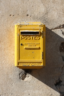 yellow steel mail box mounted on gray wall