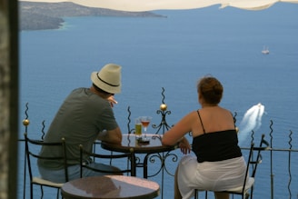 back view of man and woman sitting in front of terrace with sea view