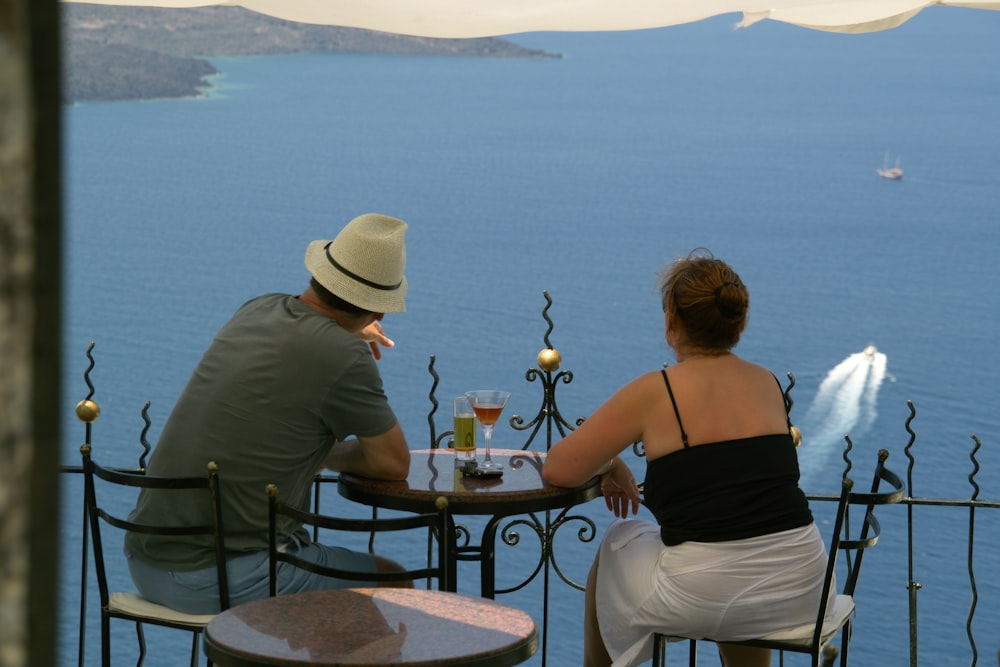 Vista trasera del hombre y la mujer sentados frente a la terraza con vista al mar
