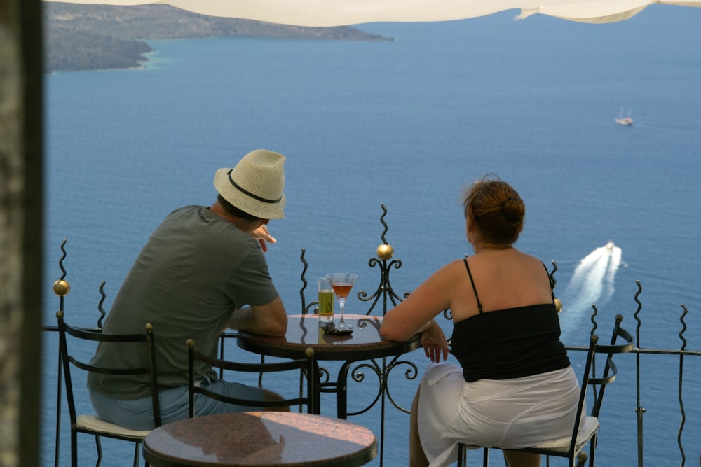 back view of man and woman sitting in front of terrace with sea view