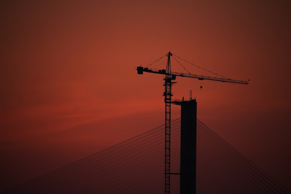 a crane is silhouetted against a red sky