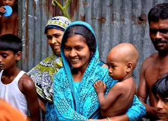 woman holding baby surrounded with people