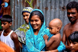 woman holding baby surrounded with people