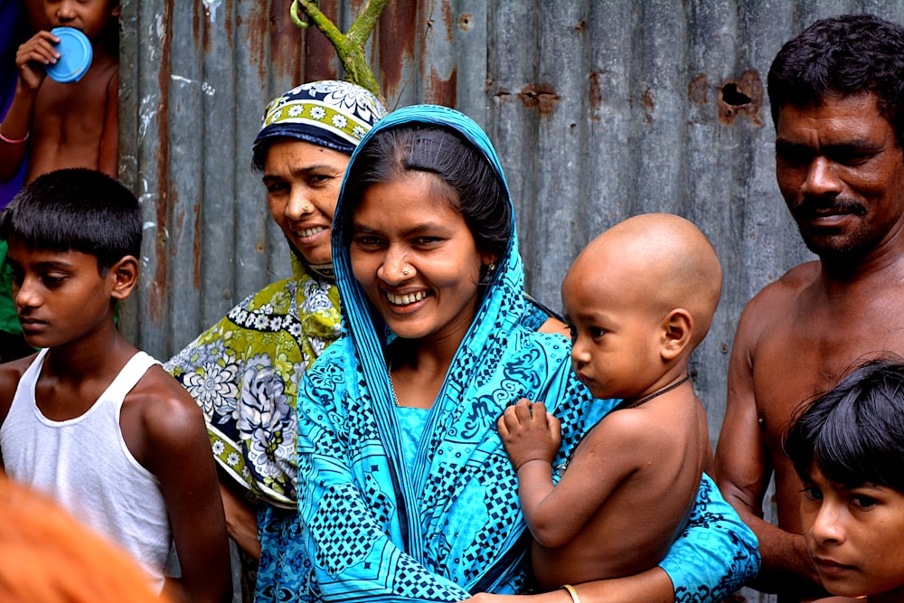 woman holding baby surrounded with people