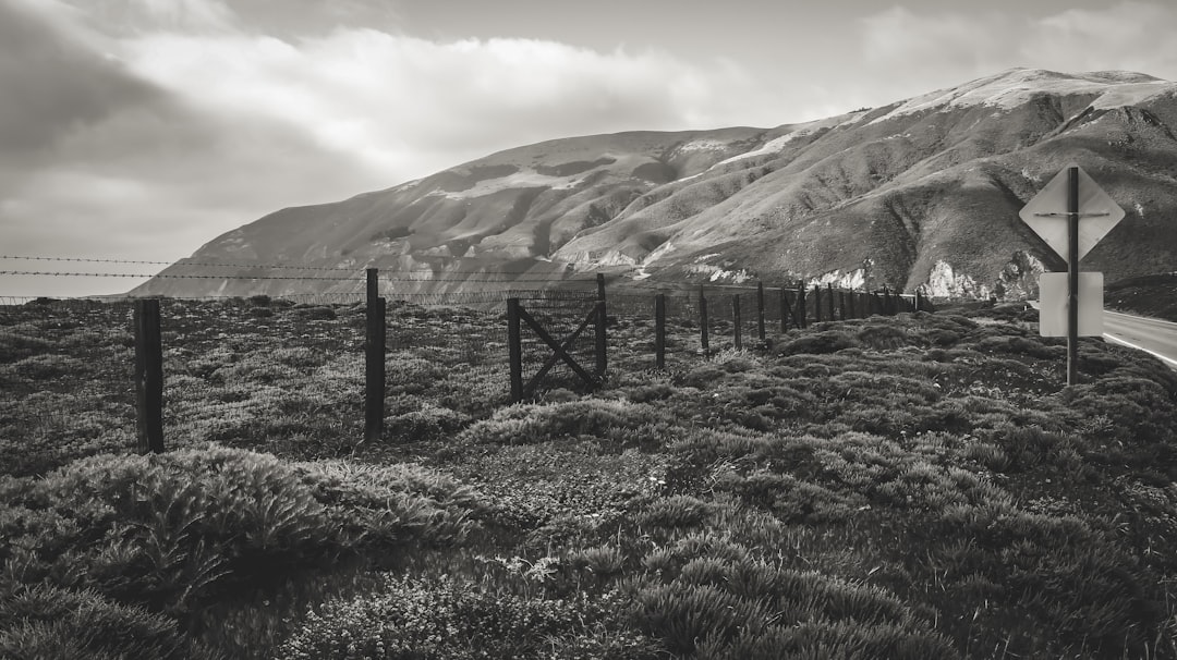 grayscale photo of fence near mountain
