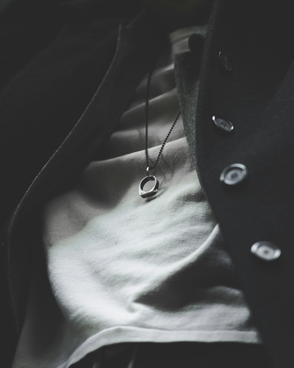 person wearing silver-colored ring pendant necklace in closeup photography