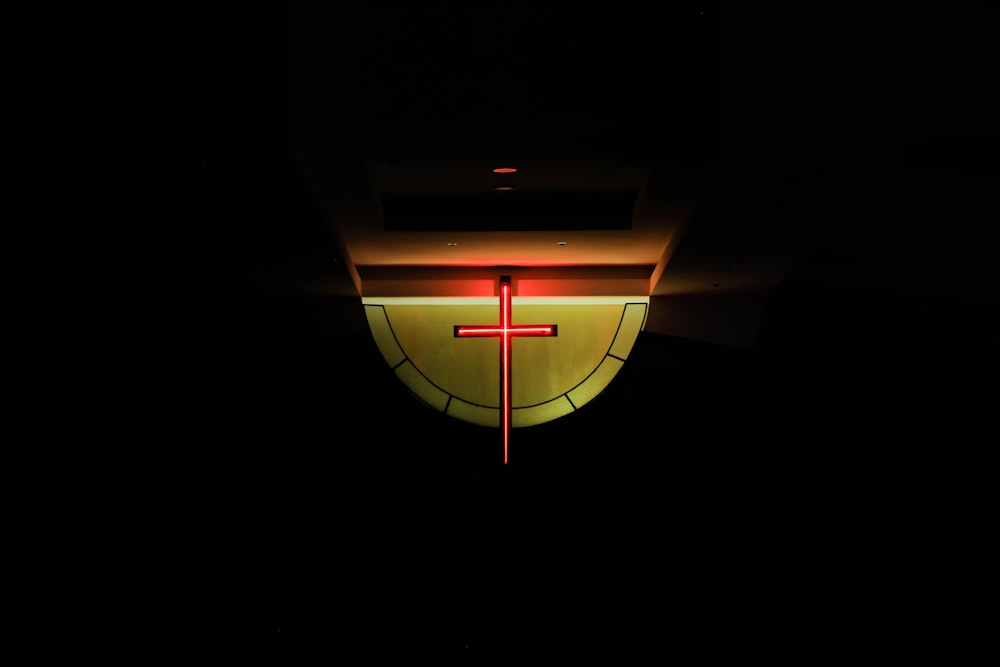 a clock with a red cross on it in the dark