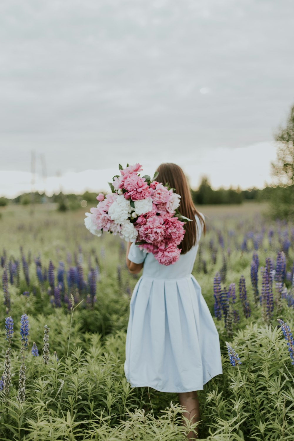 mulher que carrega flores cor-de-rosa e brancas