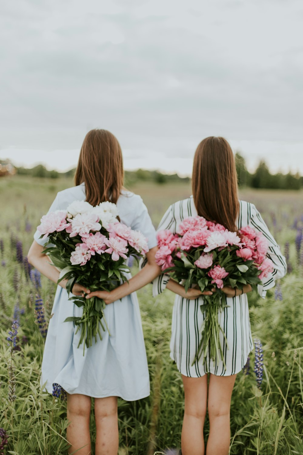 photo of two woman holding flower bouquets