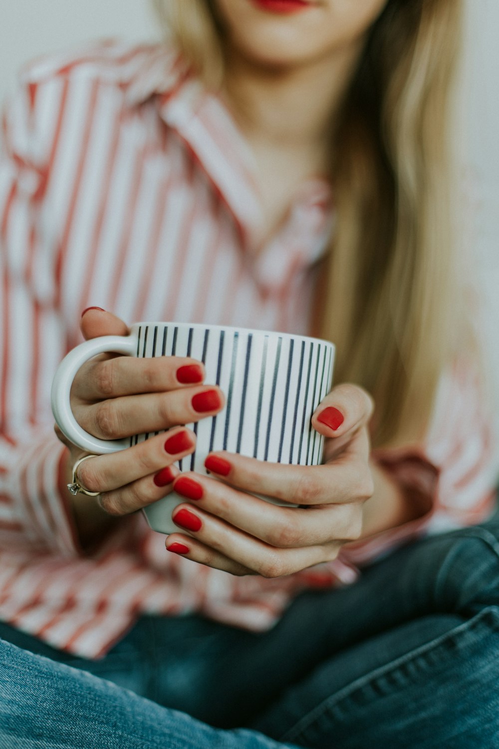 Foto de foco seletivo de uma mulher segurando uma caneca de café branca
