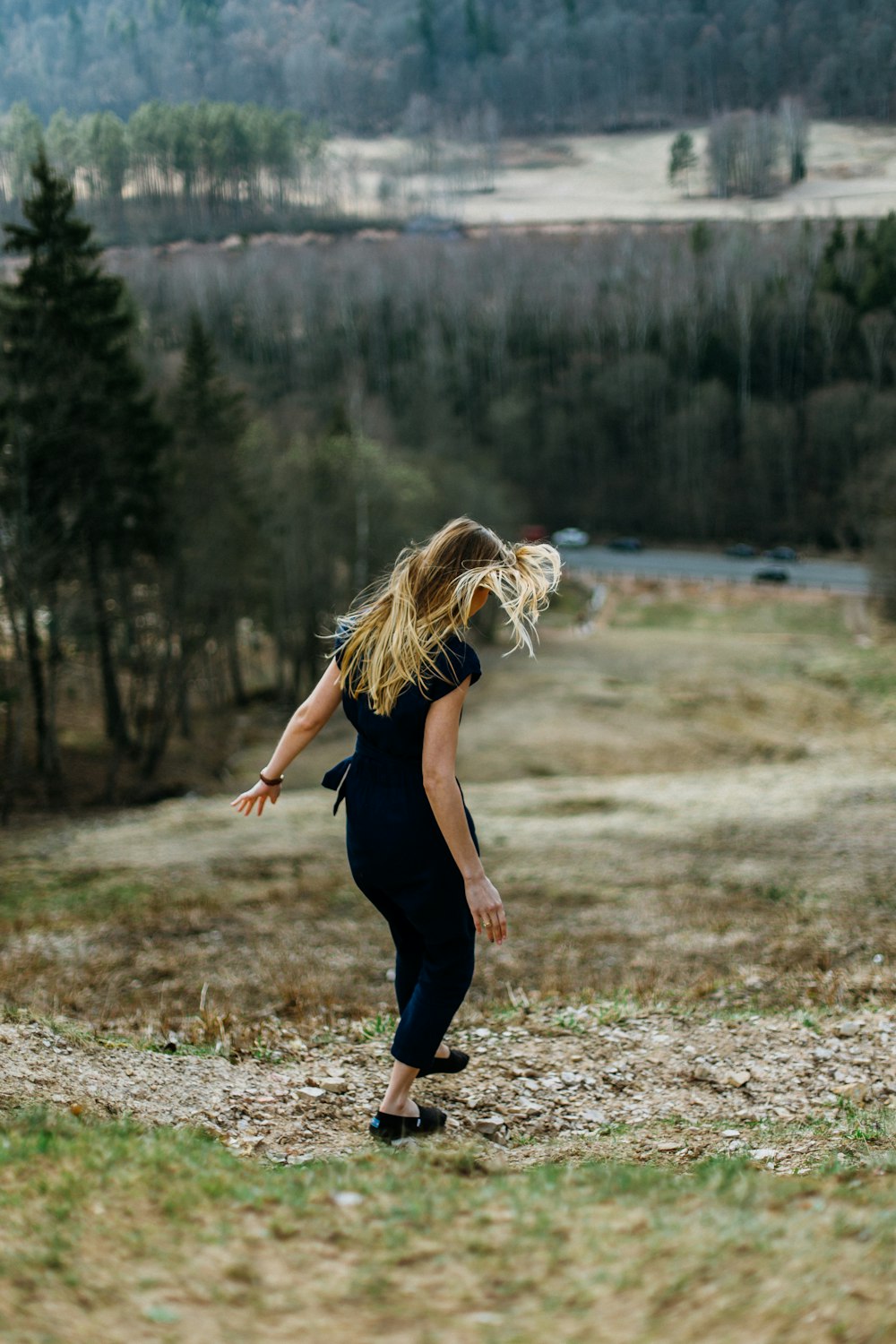 woman stepping on brown ground near road and cliff