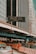An urban scene featuring tall buildings with a digital traffic sign displaying a gridlock alert. A roadway is partially visible below with construction barriers and cars. High-rise structures dominate the background, emphasizing a city environment.