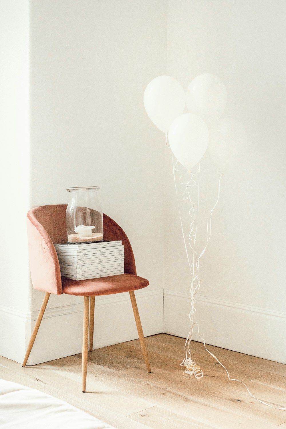 white balloons beside jar on book and chair