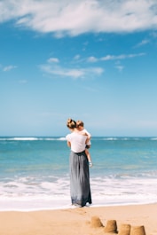 woman carrying toddler on seashore