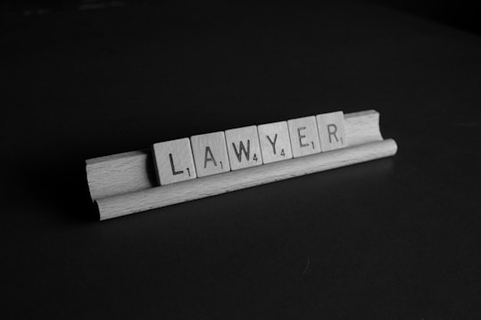 Wooden tiles spelling the word 'lawyer' are arranged on a wooden tile rack. The image is in black and white, set against a dark background.