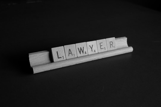 Wooden tiles spelling the word 'lawyer' are arranged on a wooden tile rack. The image is in black and white, set against a dark background.