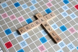 Wooden letter tiles spell out the words 'PROBATE' and 'LAWYER' on a Scrabble board. The board features a grid with colored squares marked with different point values such as 'Double Word Score' and 'Triple Letter Score'.