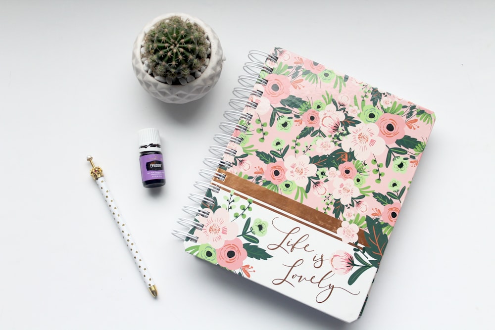 Cuaderno floral blanco y rosa sobre la mesa