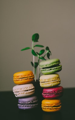 A stack of colorful mini cakes in yellow, green, and brown hues on a rustic wooden table.