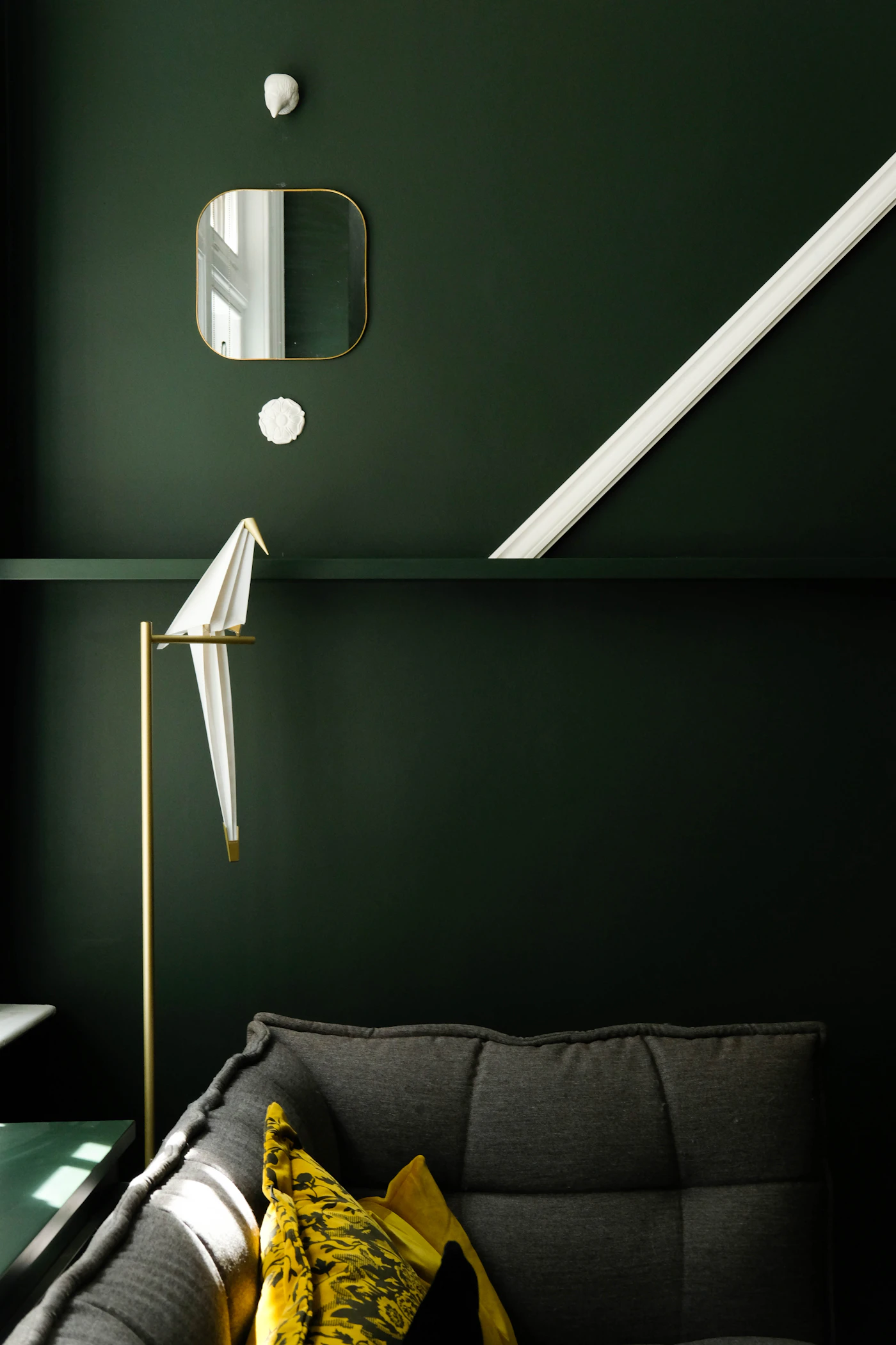 Deep green wall with a sculptural white lamp beside a sofa (placeholder photograph)