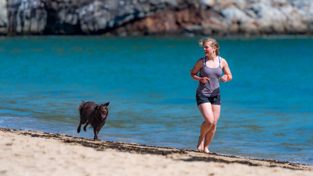 woman and dog running in seashore