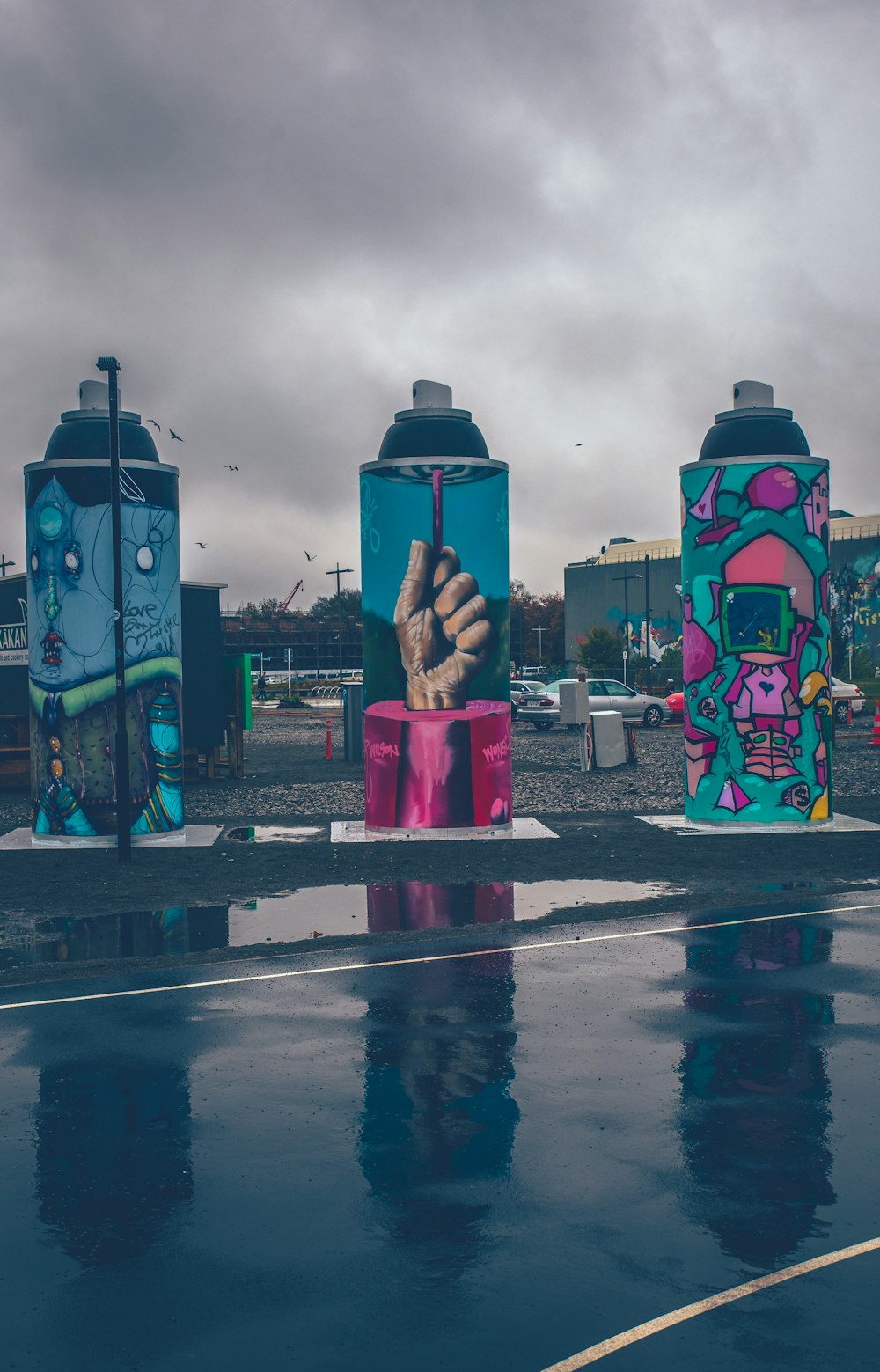 Tres estatuas con temática de botellas de spray junto a la carretera