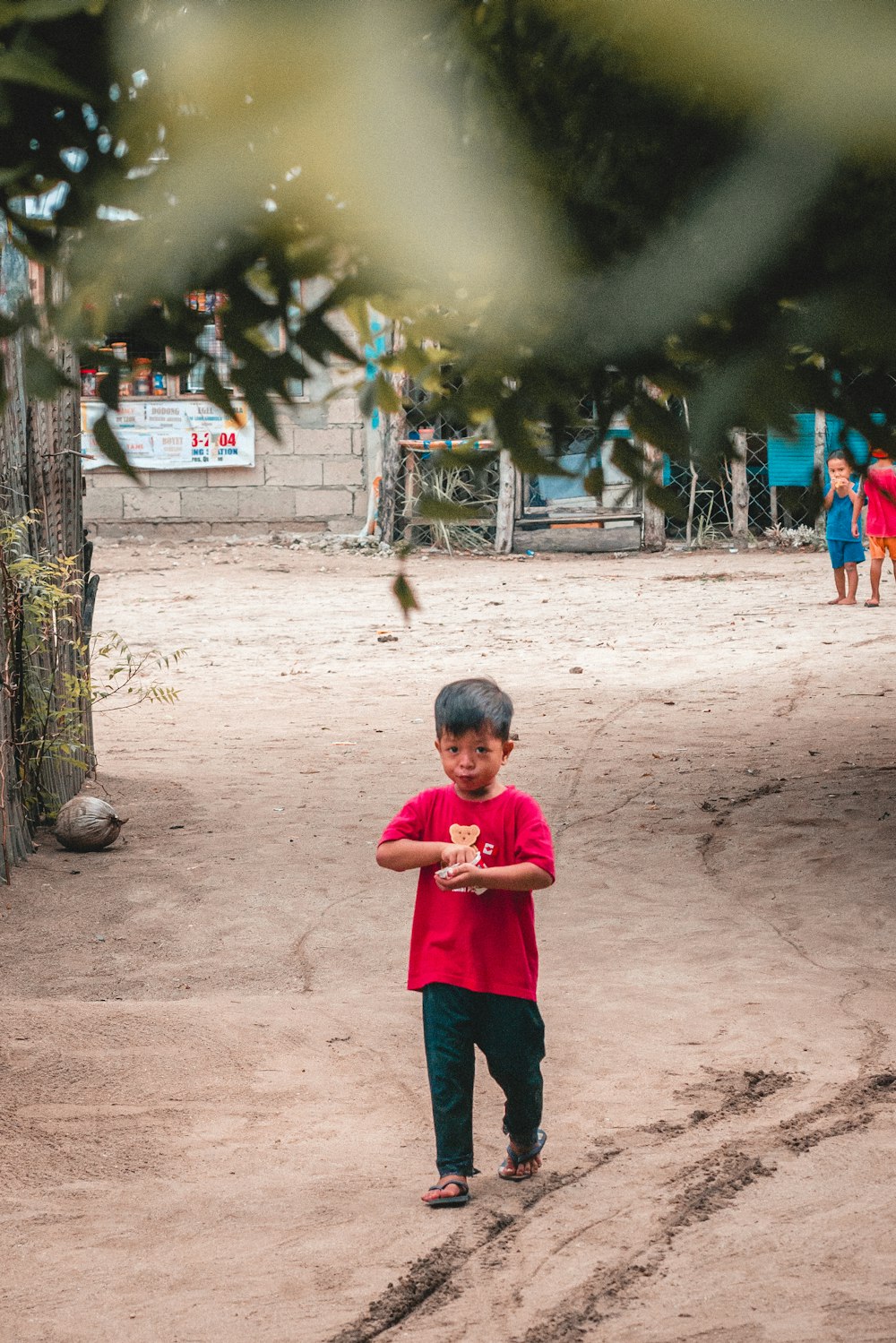 boy in pink shirt walking on dirt