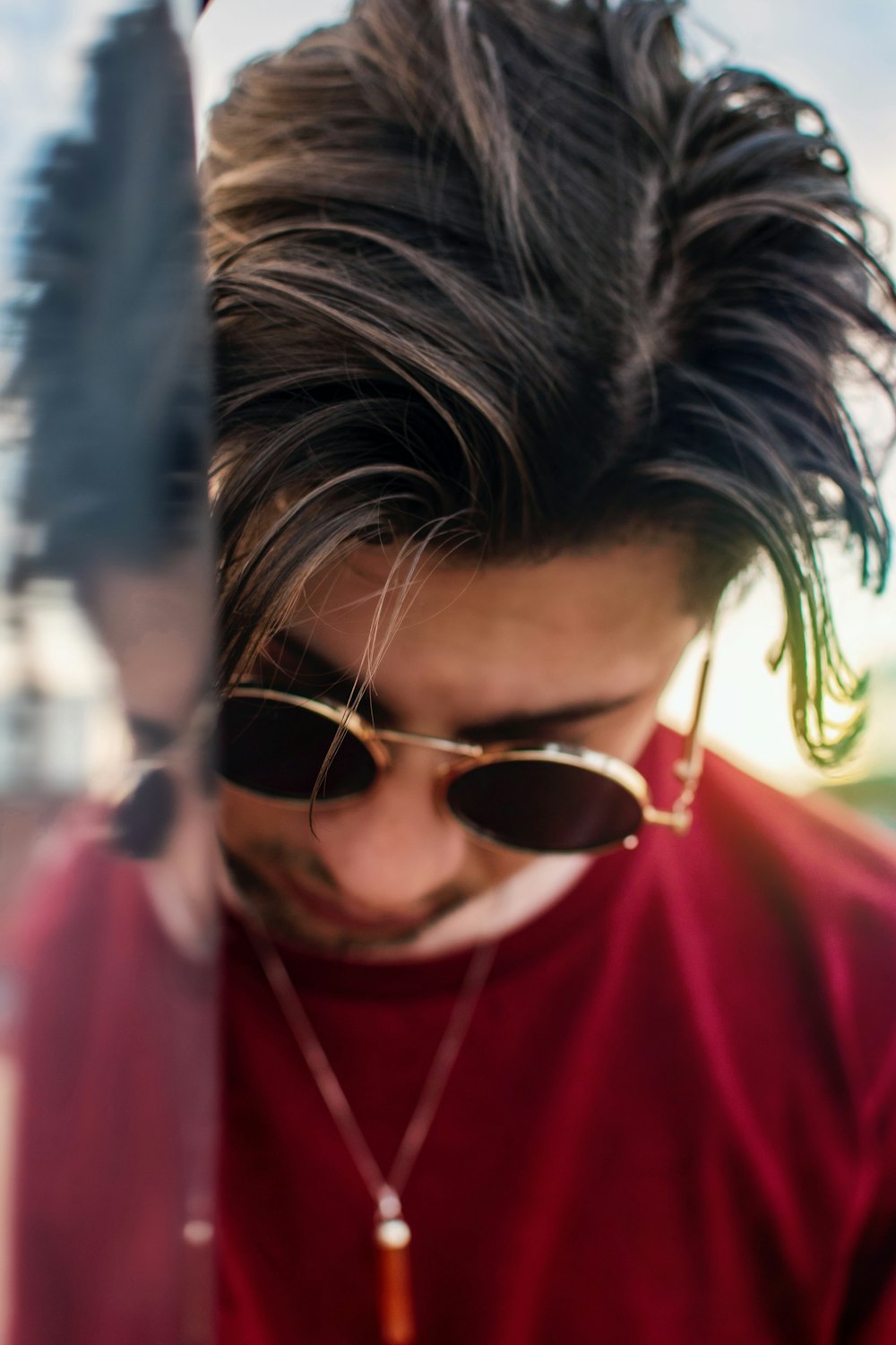 man wearing red shirt and round sunglasses