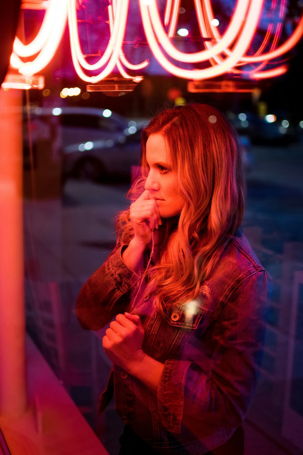 woman standing in front of clear glass wall with neon signage