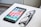 A smartphone with a colorful display of app icons is placed on a white surface next to a pair of black-framed eyeglasses.
