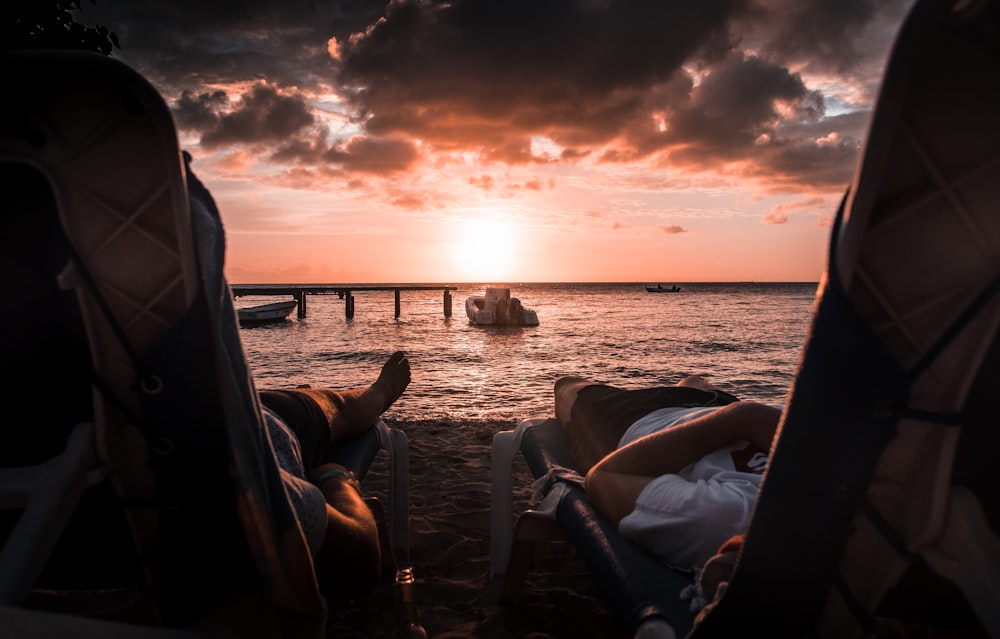 two person lying on chaise lounge under sunset