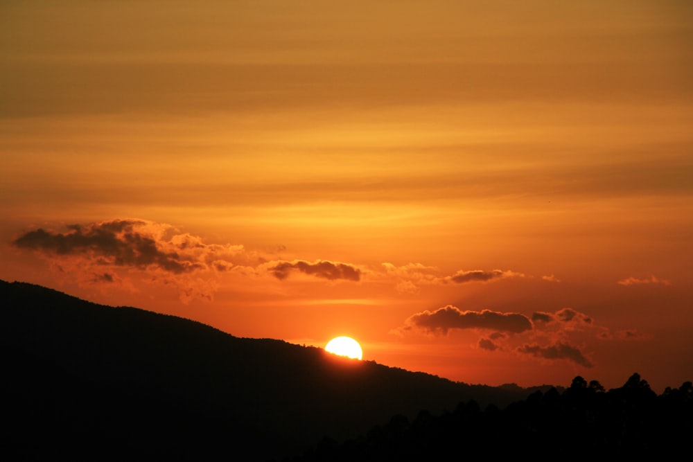 sol atrás da silhueta de uma montanha