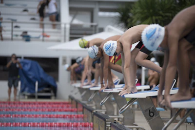A coach giving instructions to young swimmers by the poolside.