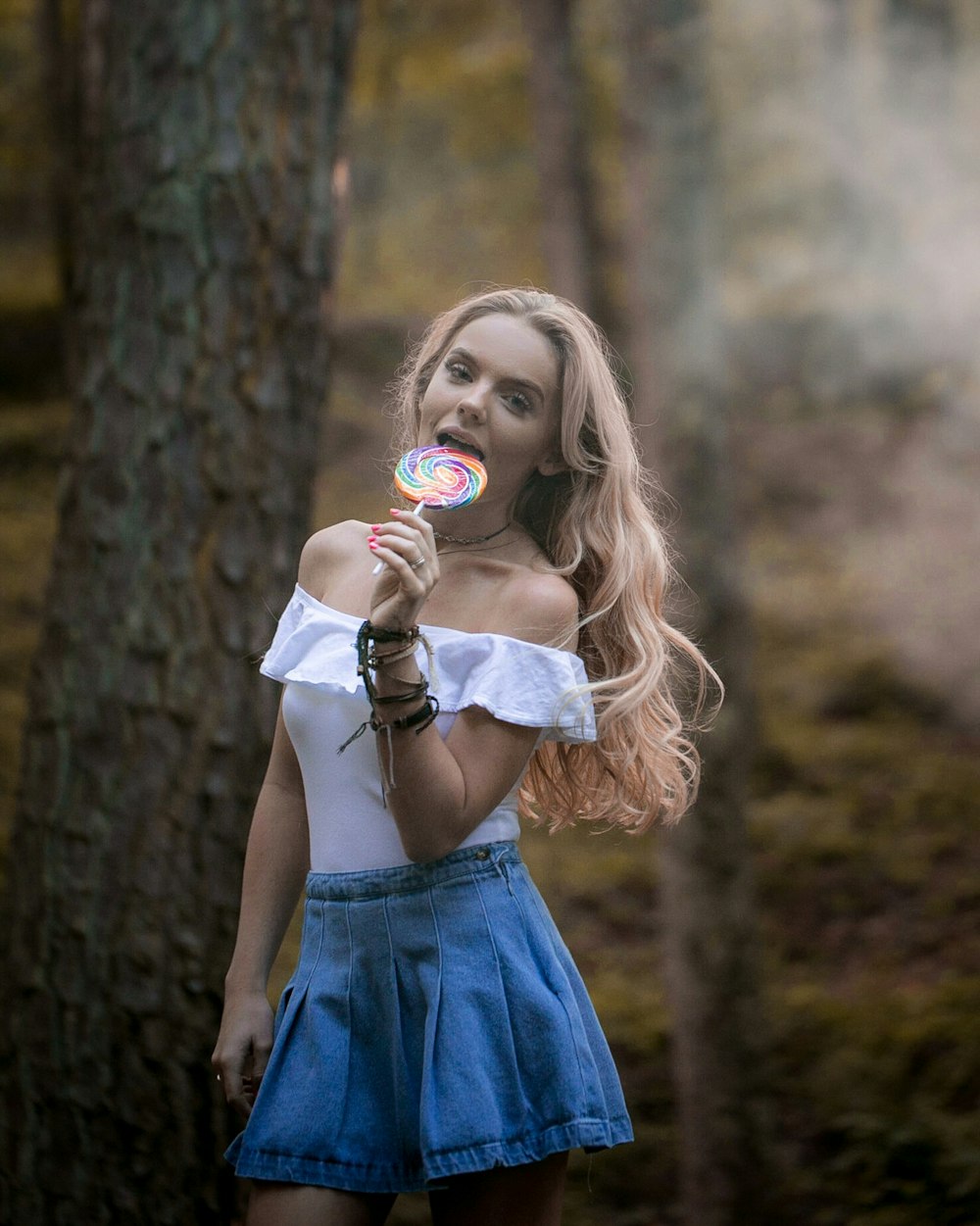 woman holding lollipop near the tree trunk