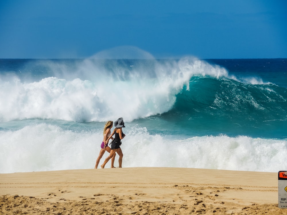 two women walking on shore