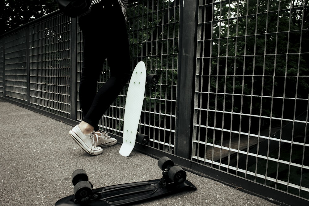 person standing near in front fence near penny board