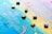 A canvas covered with overlapping vibrant colors such as blue, yellow, pink, and green, with a textured surface. Several small, square oil pastels or tiles are scattered on top of the painted canvas, adding a geometric element to the abstract background.
