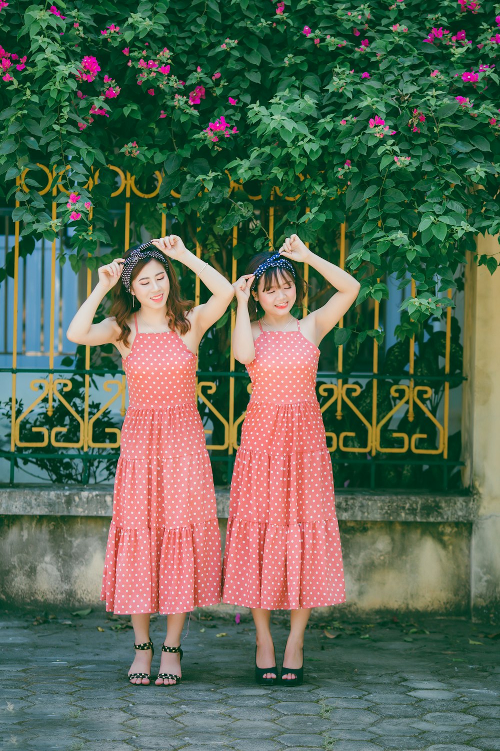 two women's wearing polka-dot dresses holding their turban headbands