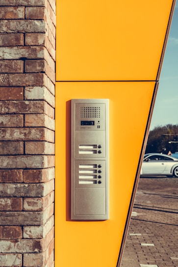 Close-up of a technician carefully installing a traditional electric intercom on a residential building.