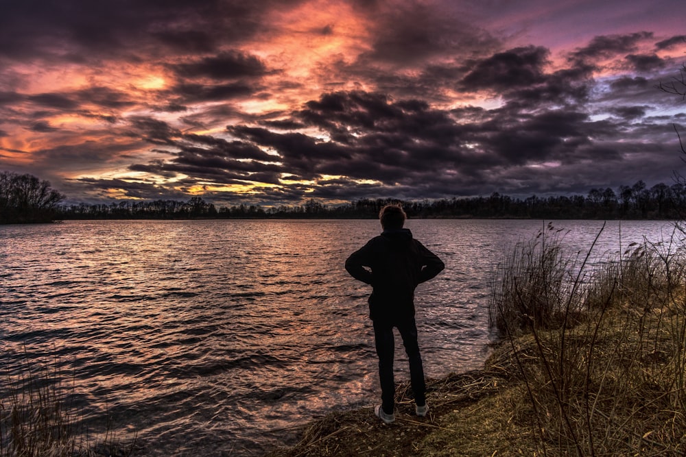 person standing near body of water during golden hour