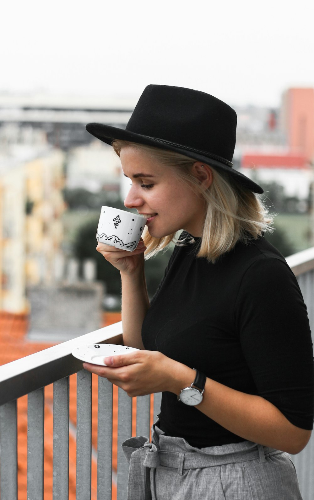 donna che beve su una tazza di caffè vicino alle ringhiere