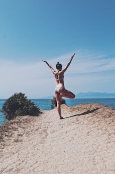 a woman in a bikini doing a yoga pose on a beach