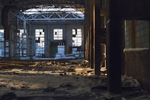Abandoned factory interior with rusted machinery and broken windows under soft natural light