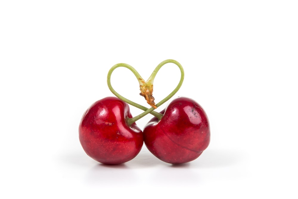 dois frutos cereja vermelhos na superfície branca